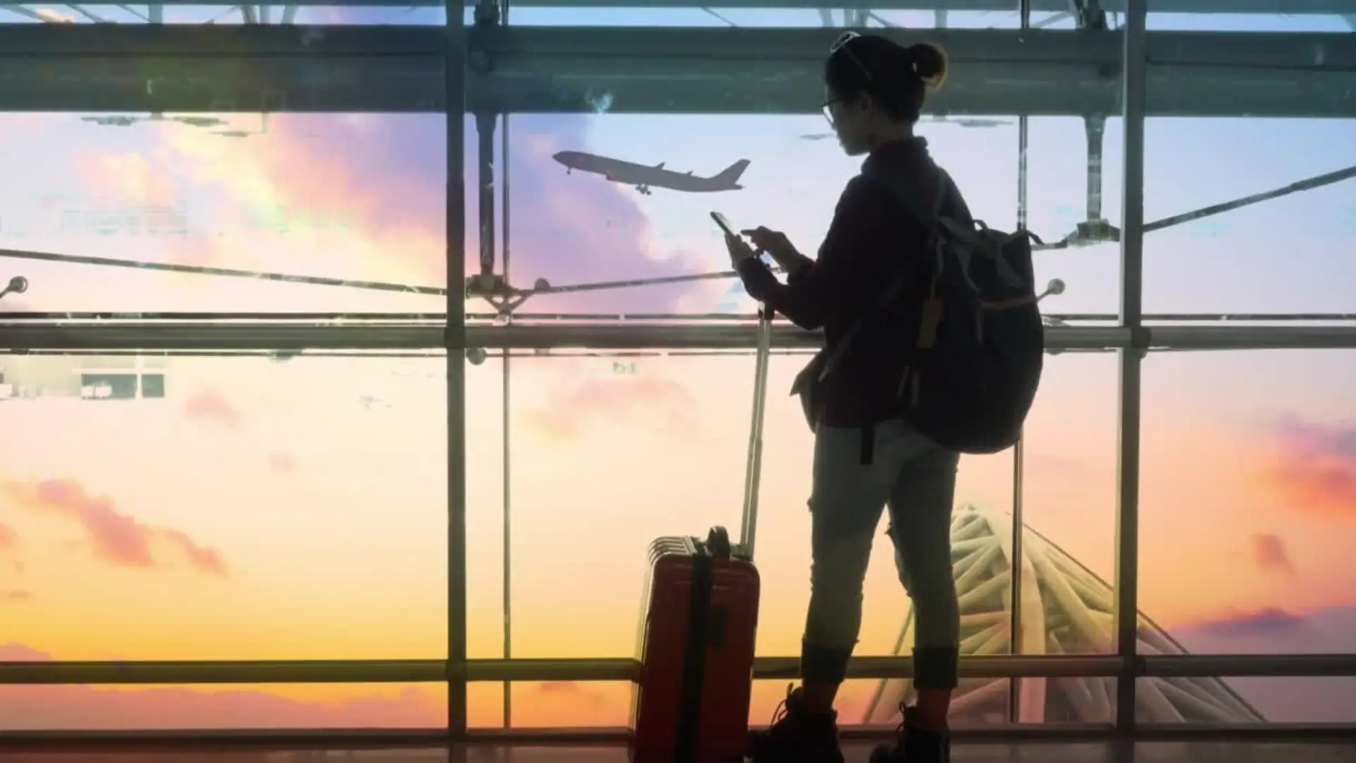 GIF animata passeggero che consulta l'ipad nel terminal, con l'aereo che decolla sullo sfondo